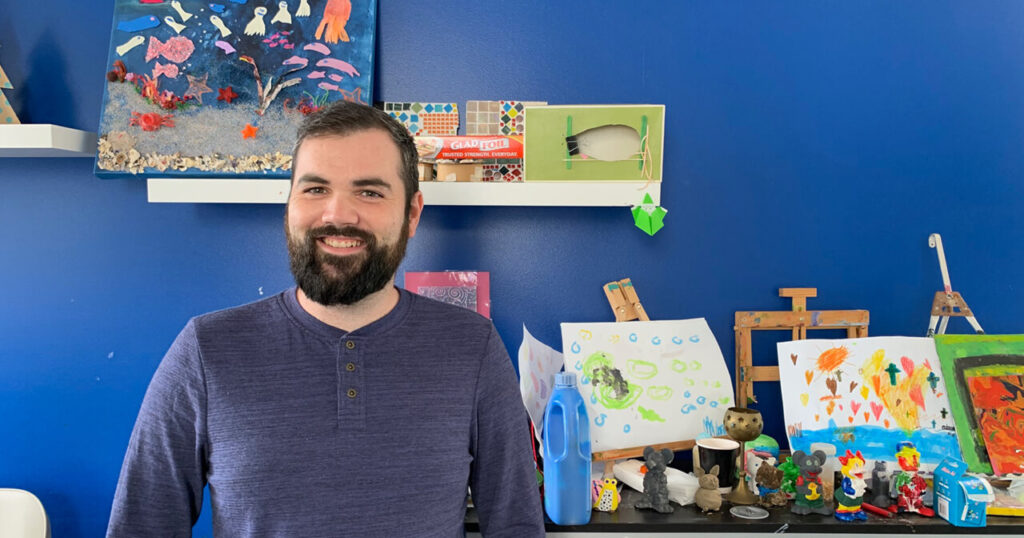 Creativity Inc staff member standing in front of artwork