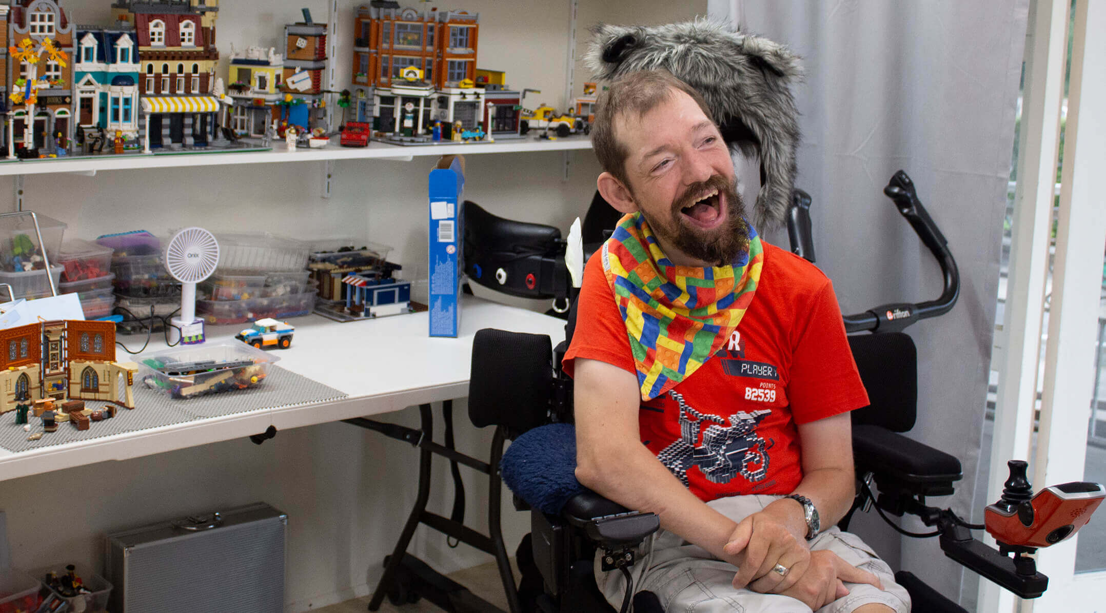 A man in a power wheelchair showing his Lego collection