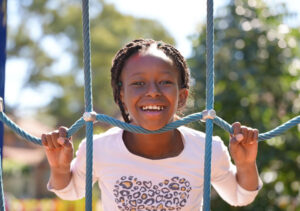 Little girl smiling, playing on climbing ropes