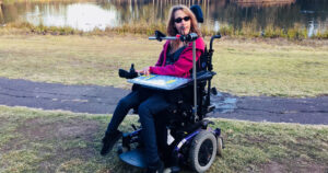 Northott customer Gretta in her wheelchair by a lake in the park