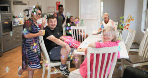 Group of people sitting at a dining table playing with bubbles