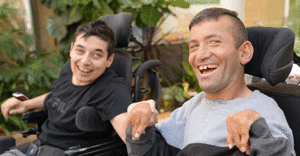 Two friends in a wheelchair holding hands