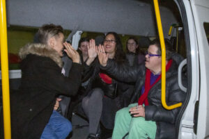 Males and females high-fiving and smiling sitting inside an accessible van