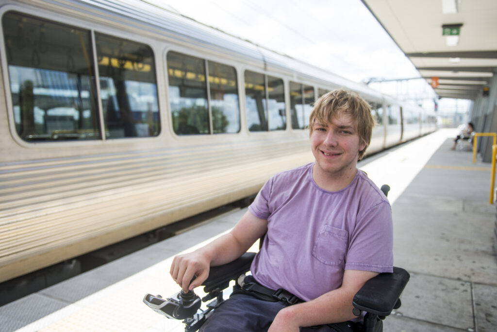Male customer in wheelchair smiling infront of a train