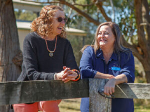 Two women leaning on a fence having a chat