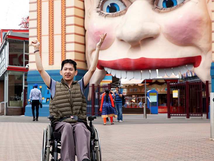 man in wheelchair with hands in the air in front of Luna Park