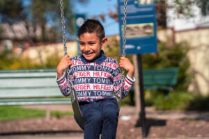 Young boy smiling on a swing at the park