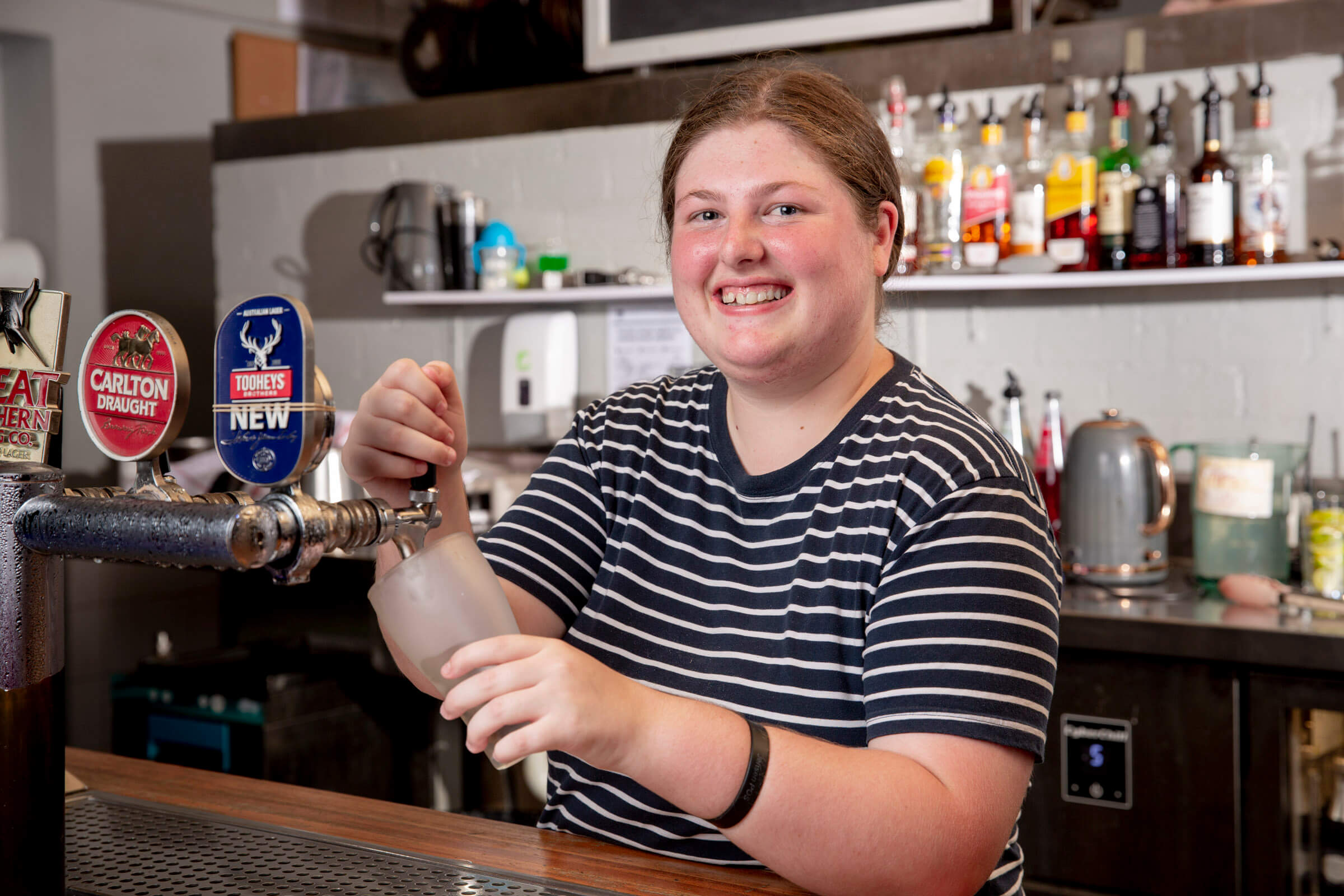 Young girl smiling pouring drinks at the bar