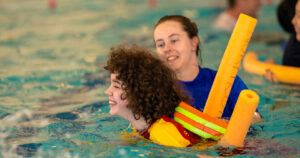 Young person with therapist swimming