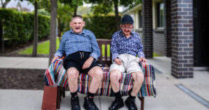 Two older males sitting and smiling