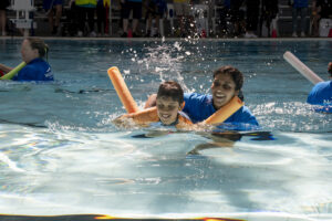 Child swimming in pool with volunteer