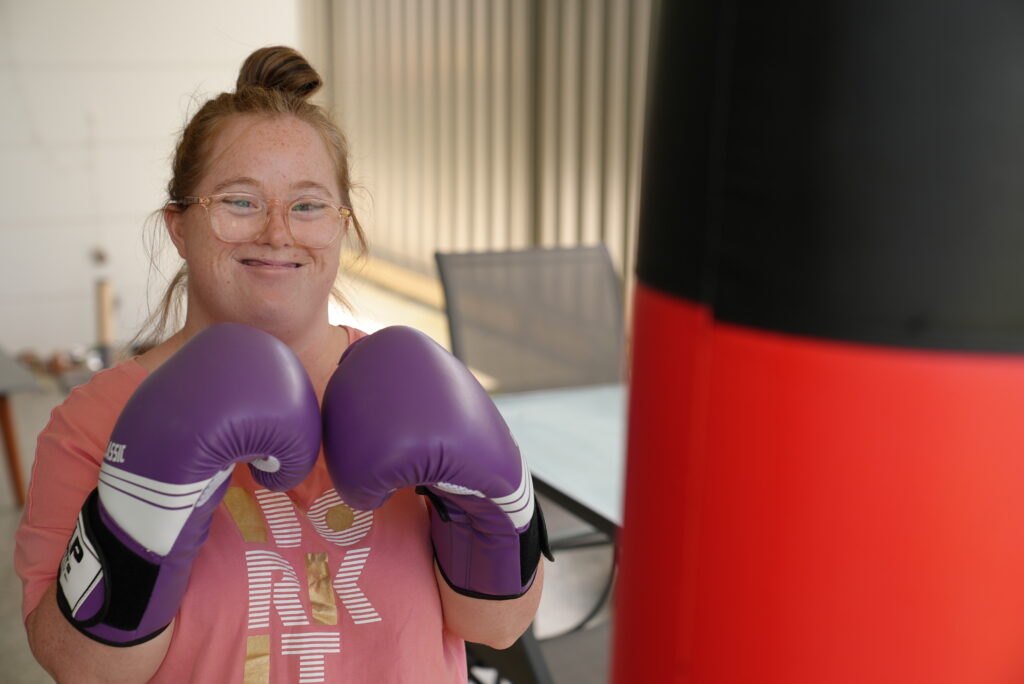 Lady posing with boxing gloves and bag.