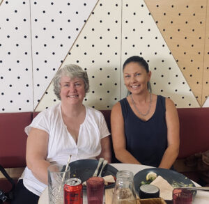 Two women smiling together in restaurant setting