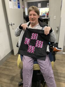 Man in wheelchair holding handmade bag