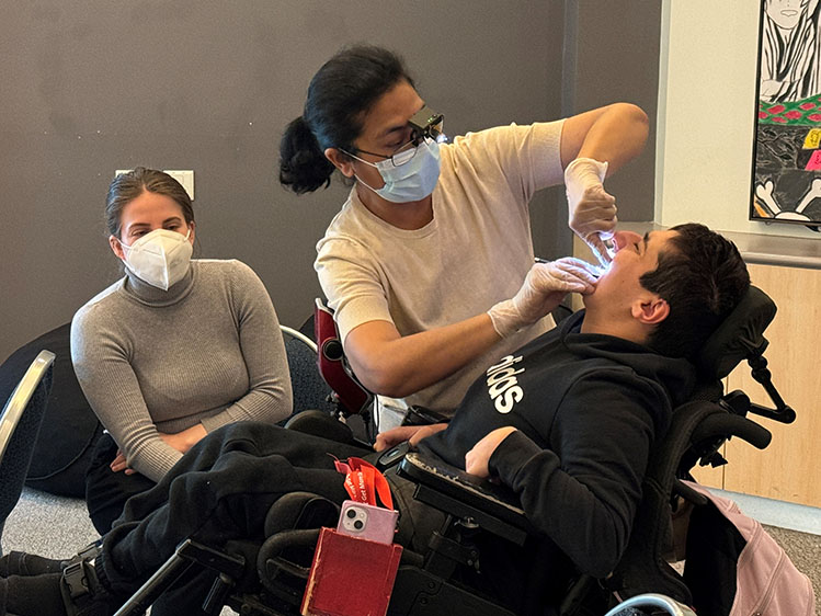 Person in wheelchair receiving a dental check up by university dentists