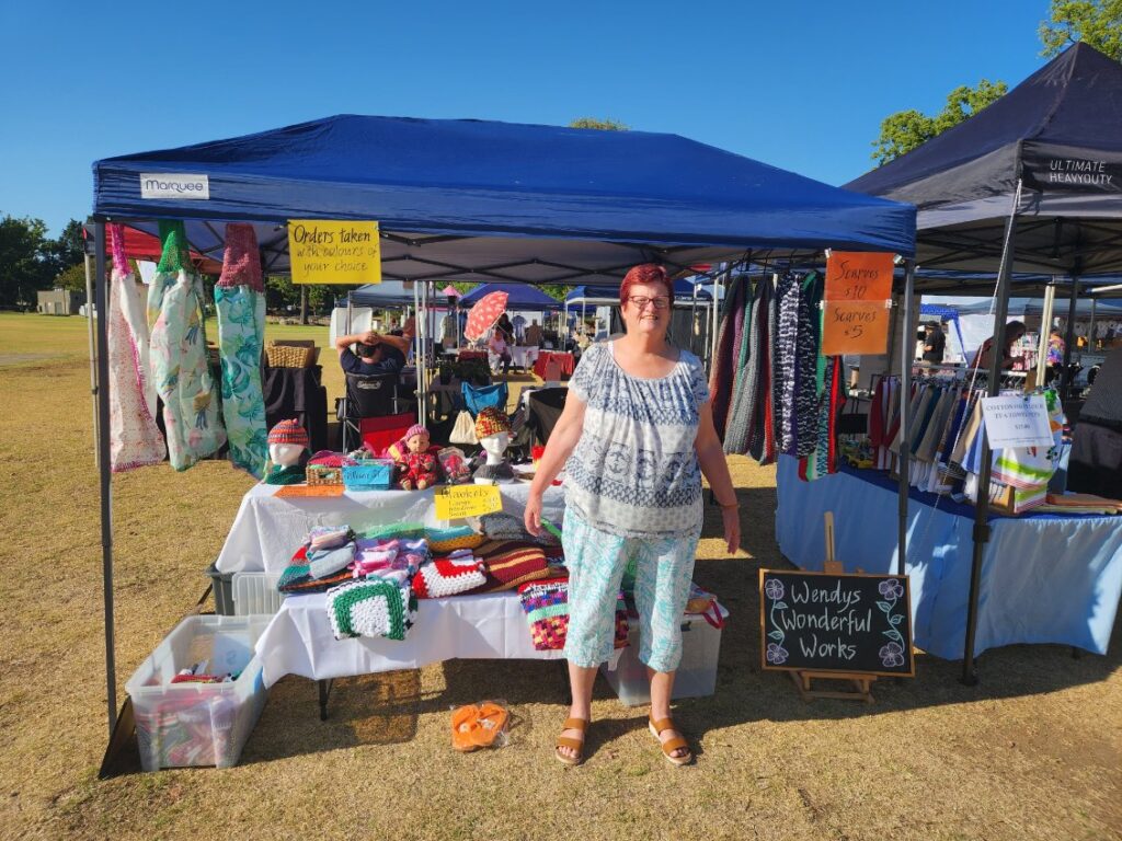 Woman standing in front of craft stall at a market.
