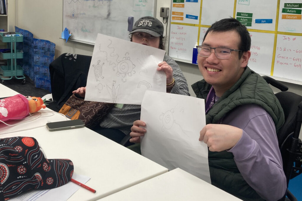 Two people are holding paper toward the camera in a Northcott office