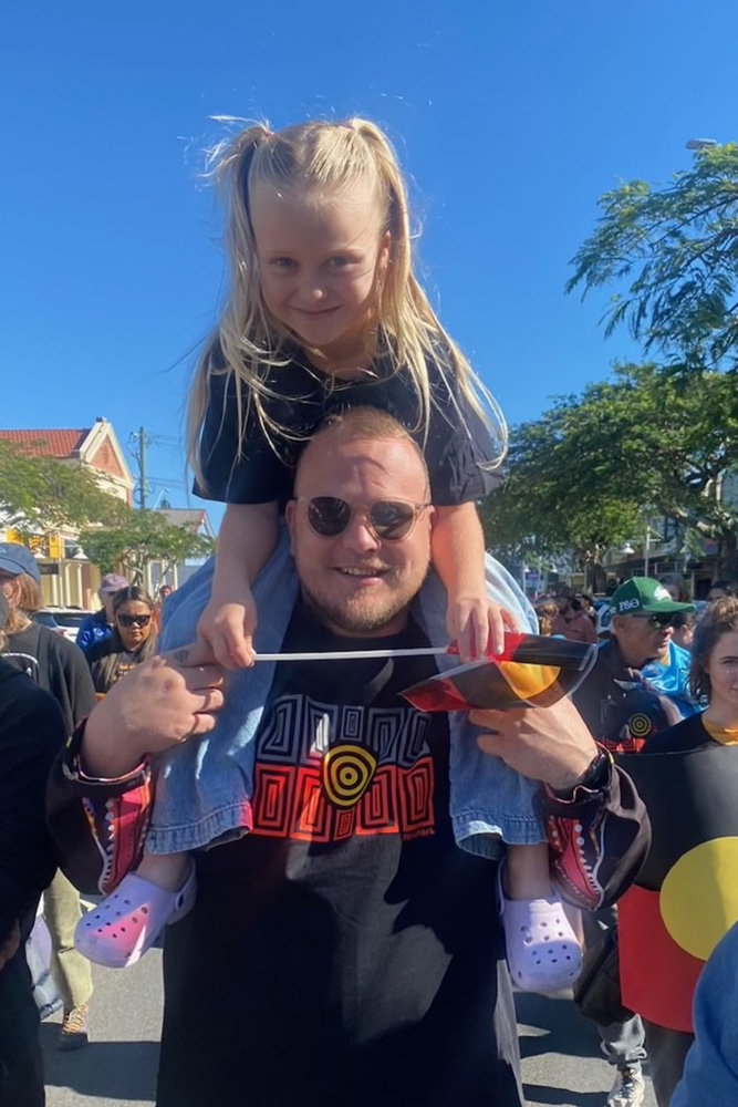 A young girl is on a man's shoulders - both are smiling