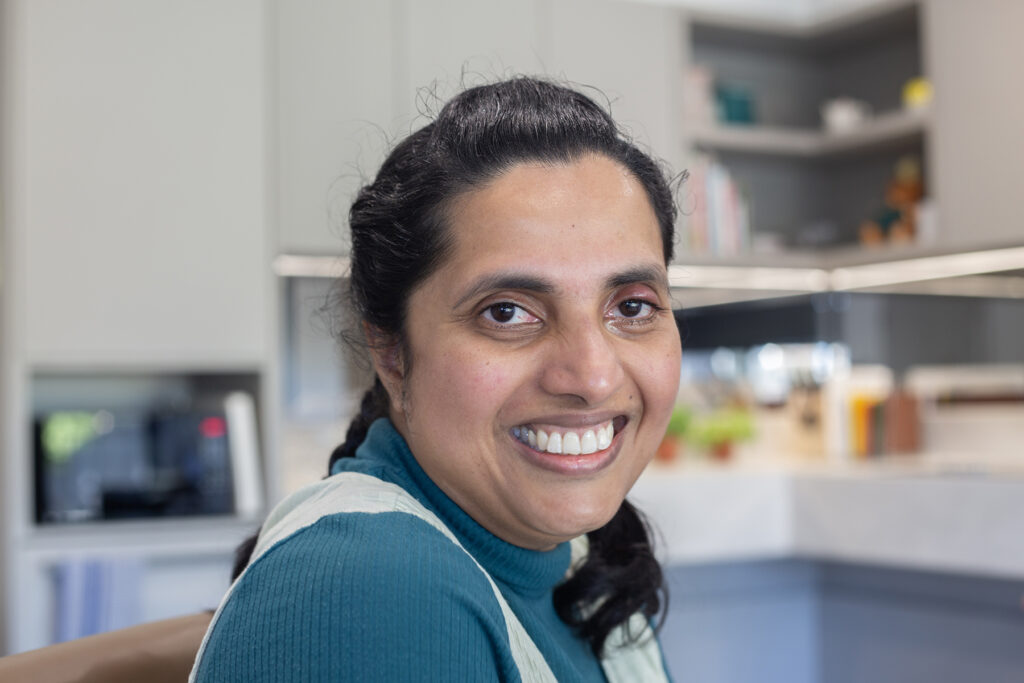 Vindya is pictured in her kitchen. She is smiling.