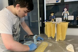 A young man is cutting fresh pasta