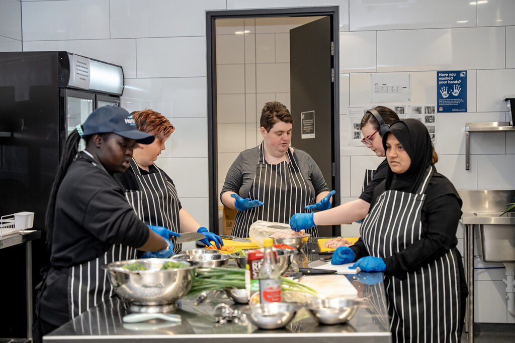 A group of young people are cooking in a commercial kitchen