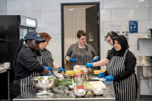 A group of young people are cooking in a commercial kitchen