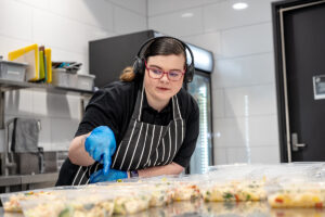 A person wearing headphones is counting some dishes in a kitchen