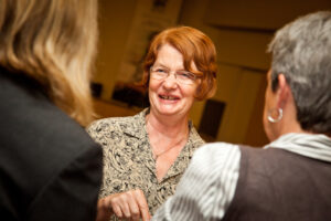 Wendy is in the centre of the photo, smiling while talking to two other people