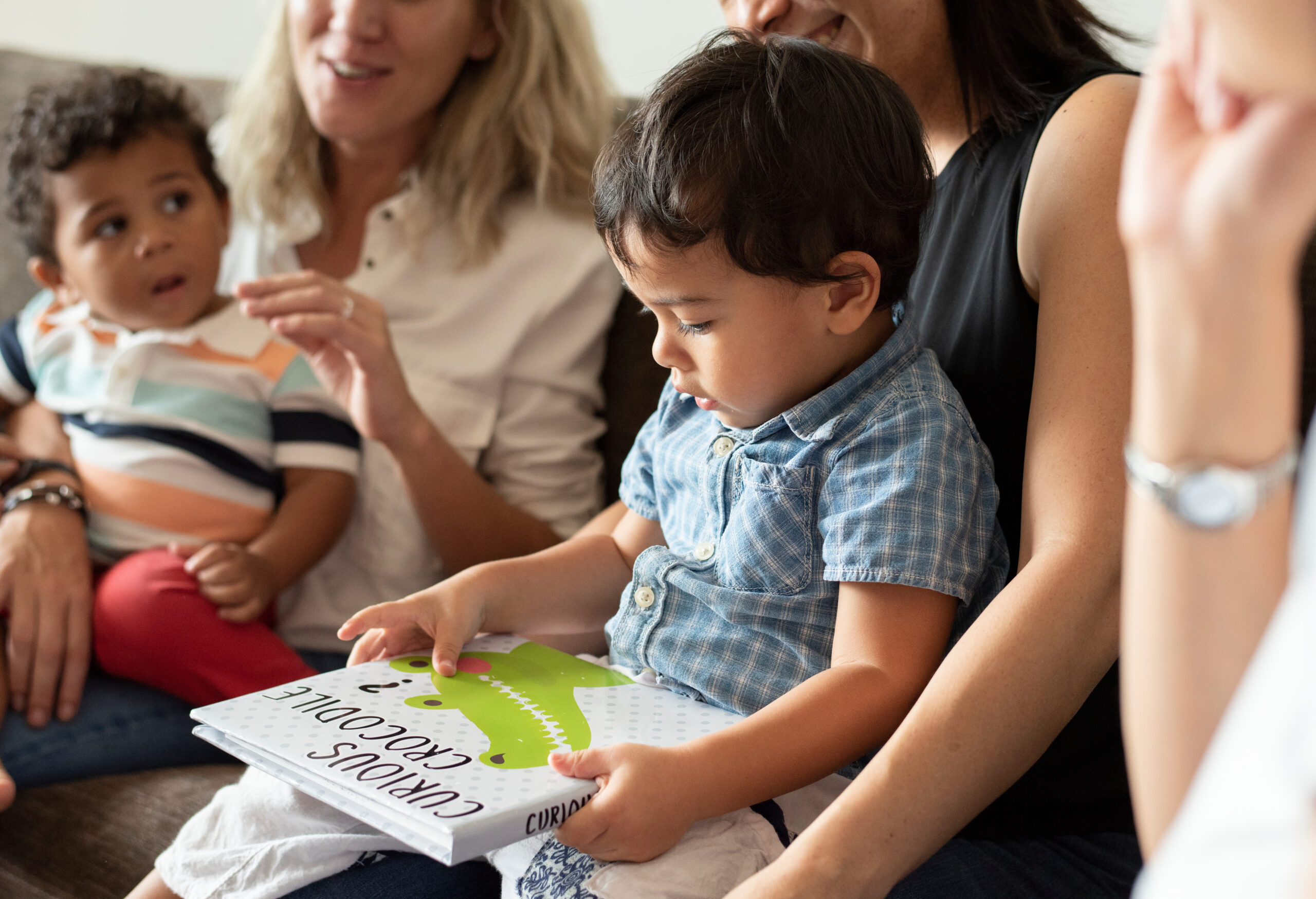 Friendly moms sitting and holding their sons on the sofa