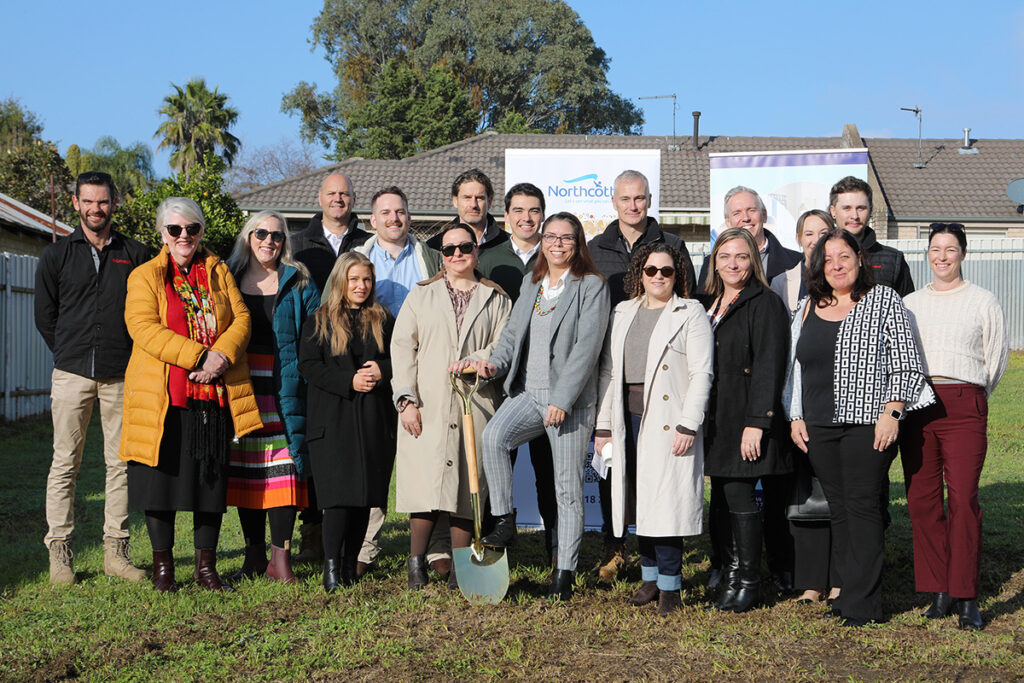 A lerge group of people pose in front of a building plot