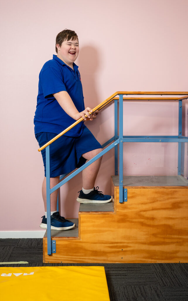 Ryker climbs a set of stairs during physio - he is smiling.