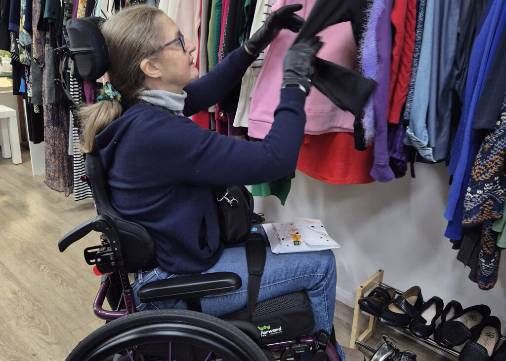 A person is looking at some clothes in a shop - they are using a purple manual wheelchair.